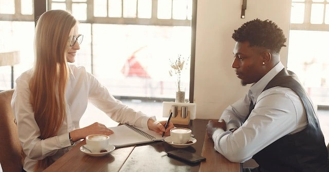 Businesswoman and -man sitting at a table with coffee discussing strategy