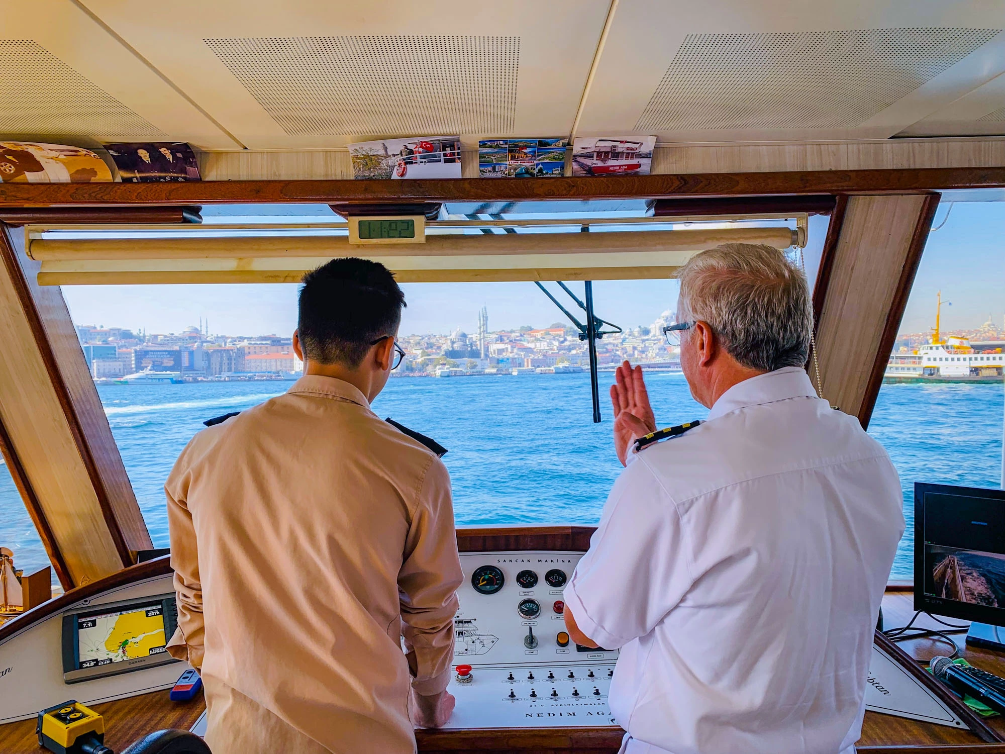 A pilot and a captain on the bridge of a ship navigating the waters